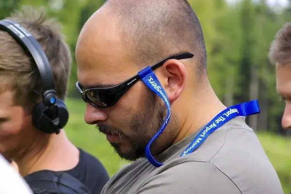 Mann mit Sonnenbrille und Headset, schaut nach unten