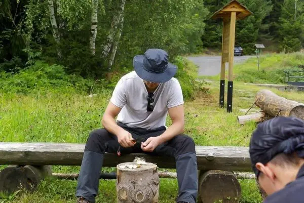 Messer bearbeitet Holzstück auf einem Baumstamm im Freien