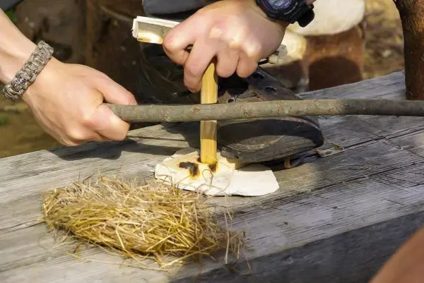 Person erzeugt Feuer mit Holz und Zunder beim Survival Training