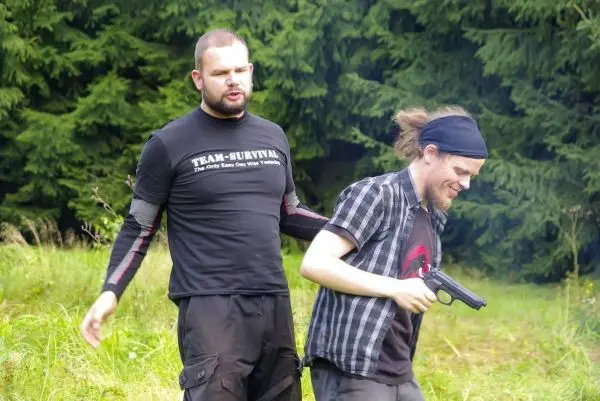 Person führt andere Person mit einer Waffe in der Hand