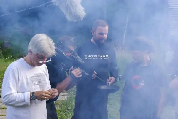 Rauch umgibt mehrere Personen, während eine Kamera auf eine Aktion gerichtet ist