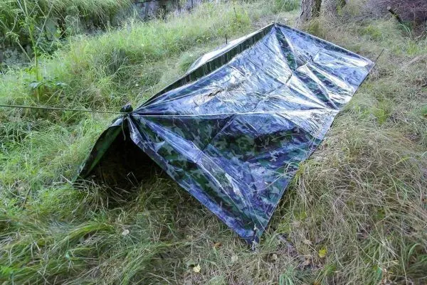 Tarp-Notunterkunft aus camouflierter Plane, mit Abspannschnur gesichert