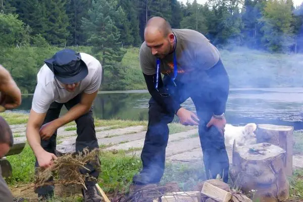 Zunder wird vorbereitet, während Rauch von einem kleinen Feuer aufsteigt
