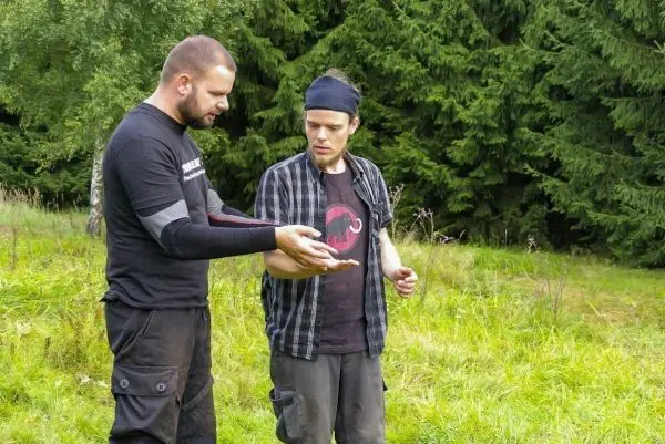 Zwei Personen betrachten gemeinsam ein Objekt in einer Wiese