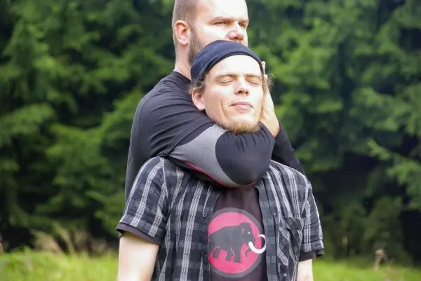 Zwei Personen in einer Trainingssituation, eine Person hält die andere im Haltegriff