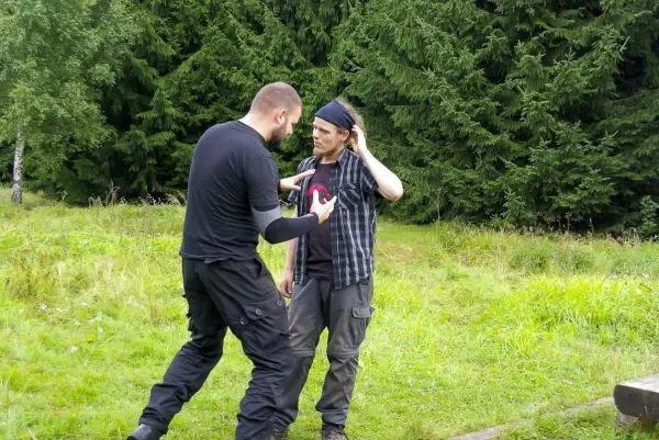 Zwei Personen stehen im Gespräch auf einer Wiese