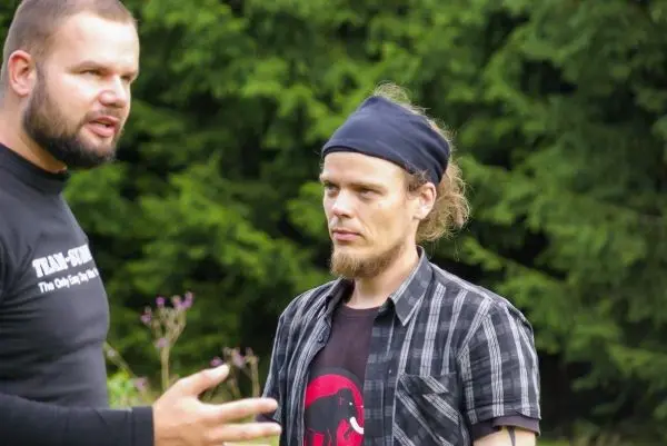 Zwei Personen stehen im Gespräch vor grüner Hintergrundvegetation