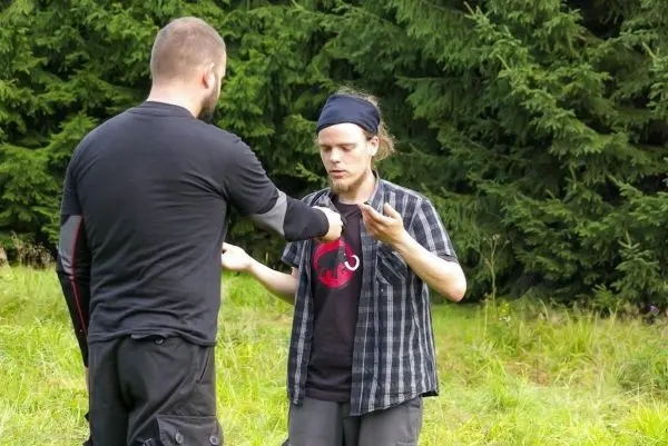 Zwei Personen stehen in einer Wiese und führen eine Übung durch