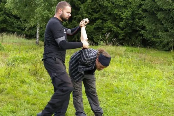 Zwei Personen üben eine Selbstverteidigungstechnik im Freien auf einer Wiese