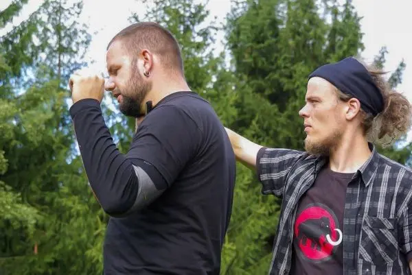 Zwei Personen üben eine Technik zur Selbstverteidigung im Freien