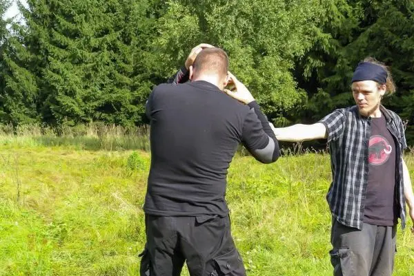 Zwei Personen üben eine Technik zur Selbstverteidigung im Freien