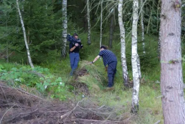 Zwei Personen untersuchen den Boden im Wald zwischen Bäumen