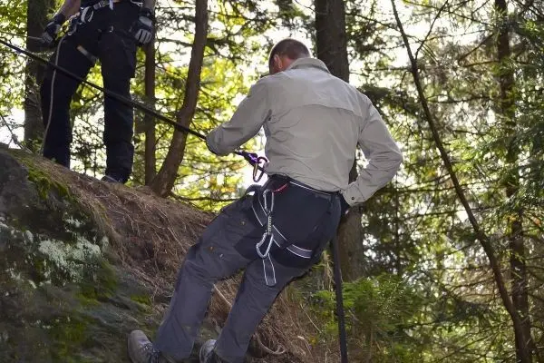 Abseilen an einem Felsen mit Sicherungsseil und Karabiner