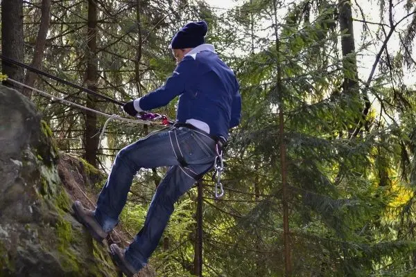 Abseilen an einem Felsen mit Sicherungsseil und Klettergurt