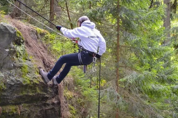 Abseilen an einem Felsvorsprung mit Sicherungsseil und Kletterausrüstung