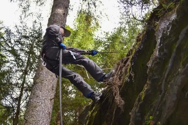 Abseilen an einem steilen Felsen mit Sicherungsseil und Kletterausrüstung