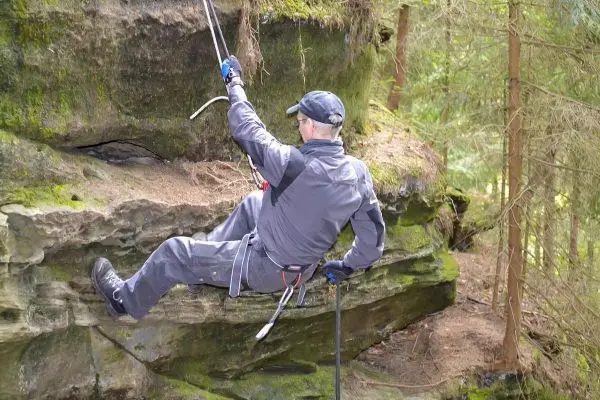 Abseilen an einer Felswand mit Sicherungsseil und Karabiner