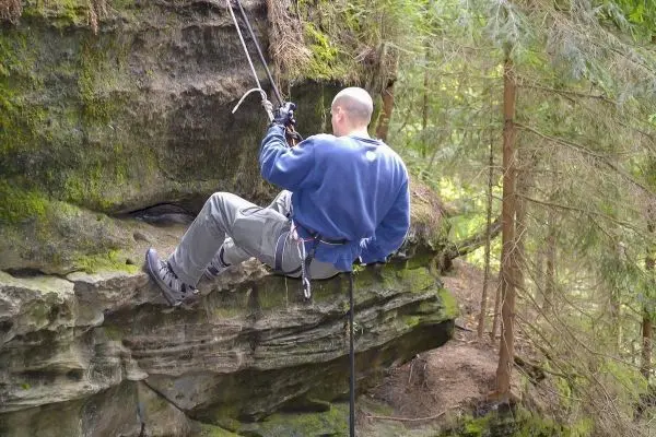 Abseilen an einer Felswand mit Sicherungsseil und Karabiner