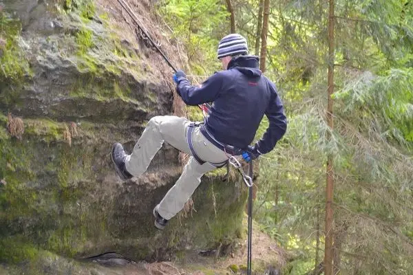 Abseilen an einer Felswand mit Sicherungsseil und Kletterausrüstung