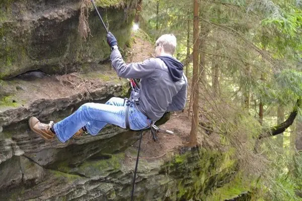 Abseilen an einer Felswand mit Sicherungsseil und Kletterausrüstung