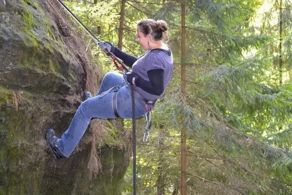 Abseilen an einer Felswand mit Sicherungsseil und Kletterausrüstung