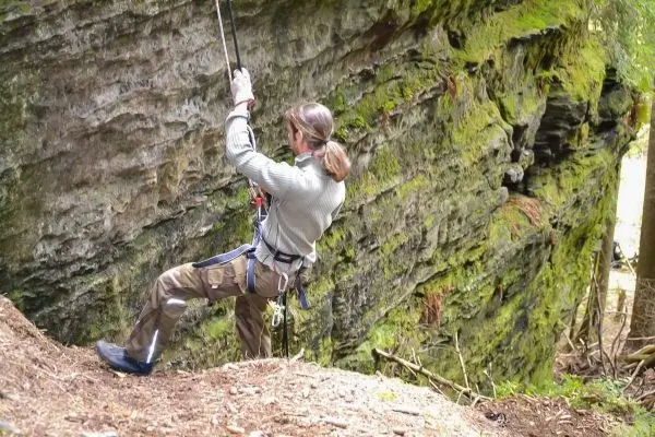 Abseilen an einer Felswand mit Sicherungsseil und Kletterausrüstung