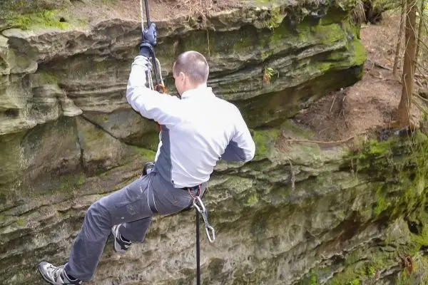 Abseilen an einer Felswand mit Sicherungsseil und Klettergurt