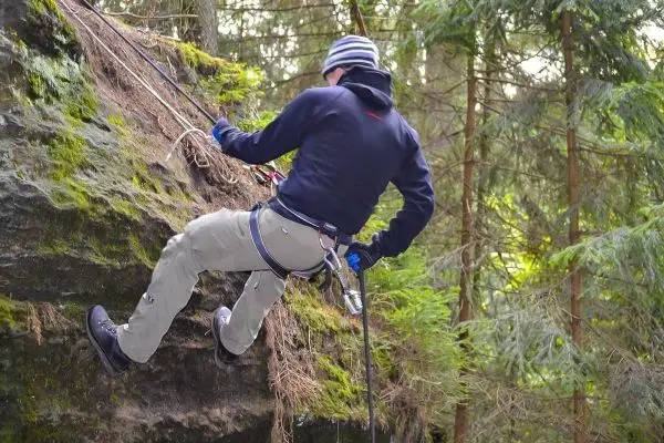 Abseilen an einer Felswand mit Sicherungsseil und Klettergurt
