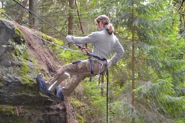 Abseilen an einer Felswand mit Sicherungsseil und Klettergurt