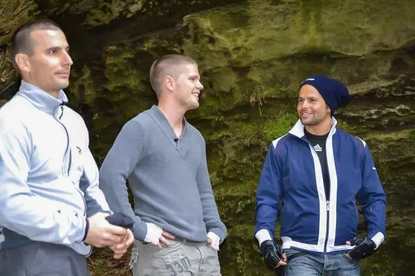 Drei Männer stehen vor einer Felswand und unterhalten sich