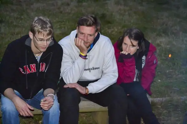 Drei Personen sitzen auf einer Bank und schauen nachdenklich