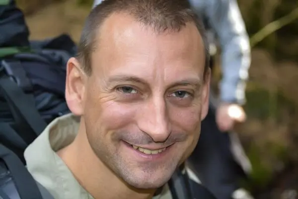 Lächelnder Mann mit Rucksack im Wald