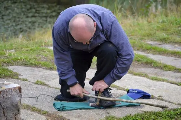 Mann bearbeitet Holzstück mit einem Messer auf einer Unterlage