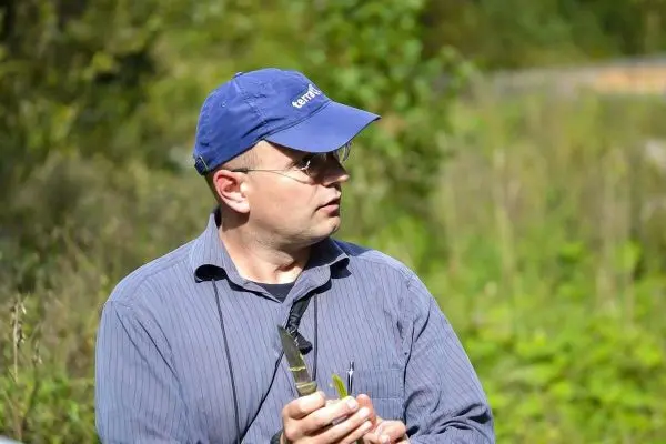 Mann hält ein Werkzeug in der Hand, umgeben von grüner Vegetation