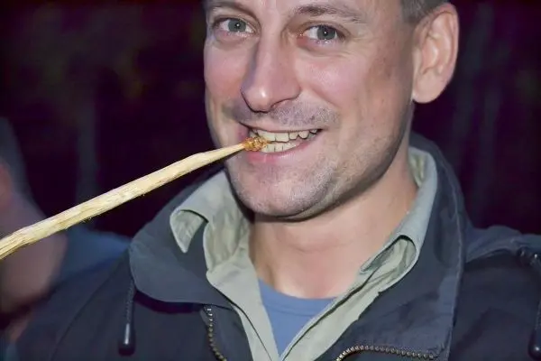 Mann hält einen Stock im Mund und lächelt