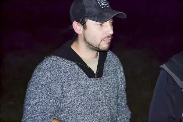 Mann spricht in dunkler Umgebung, trägt einen Pullover und eine Mütze