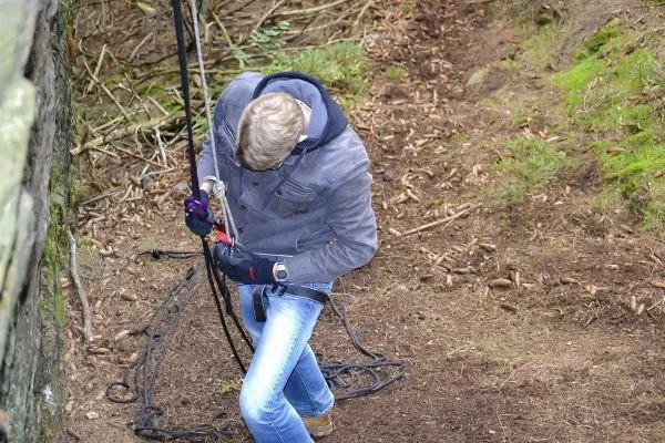 Person befestigt Seil an einem Felsen für eine Seilquerung