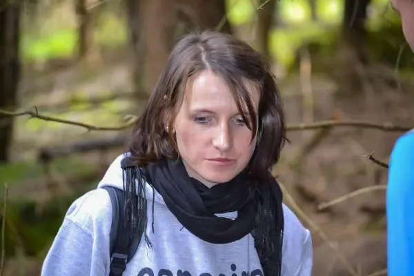 Person schaut nachdenklich auf den Boden im Wald