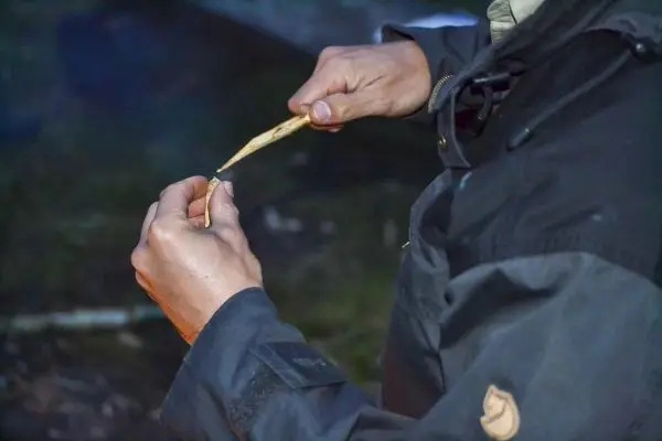 Person schnitzt mit einem Messer an einem Holzstück