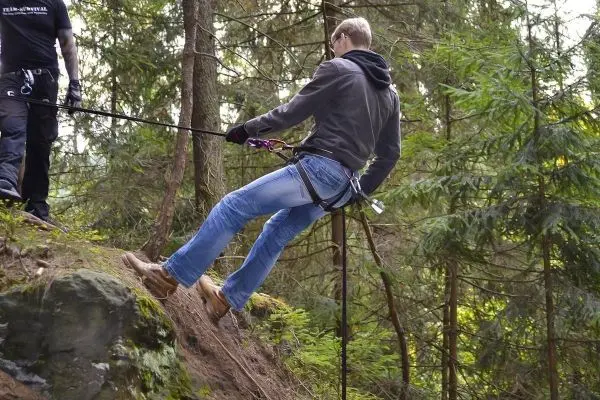 Person seilt an einem Abseilgerät einen Hang hinunter