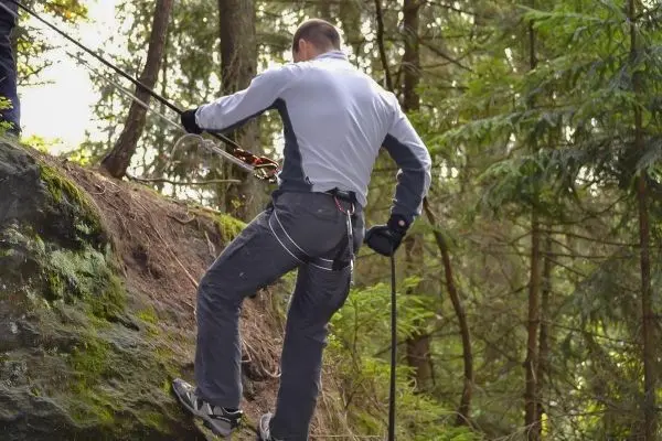 Person seilt an einem Felsen mit Sicherungsseil und Karabiner