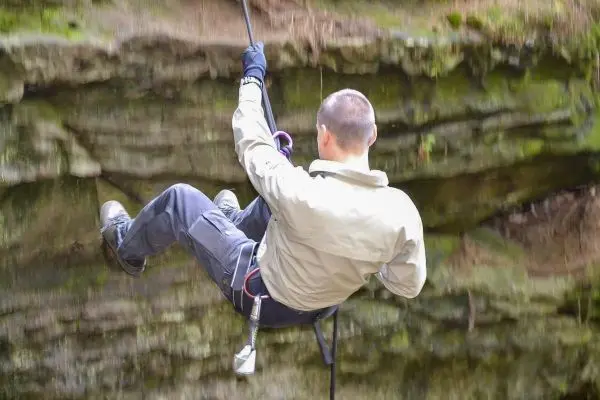 Person seilt an einem Seil entlang einer Felswand ab