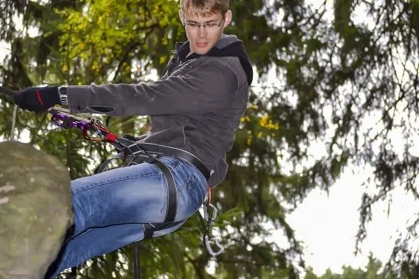 Person seilt mit Kletterausrüstung an einem Baum herunter