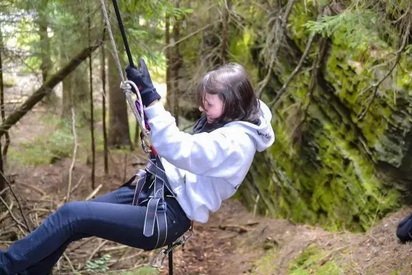 Seilquerung mit Kletterausrüstung in bewaldeter Umgebung