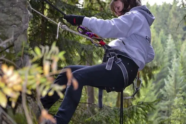 Seilquerung mit Klettergurt und Karabiner in bewaldeter Umgebung