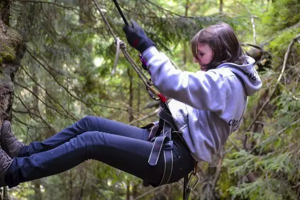 Seilquerung mit Sicherungsgurt und Karabiner zwischen Bäumen