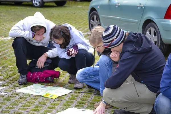 Vier Personen betrachten gemeinsam eine Karte auf dem Boden