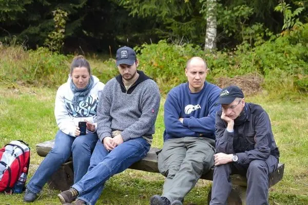 Vier Personen sitzen auf einer Holzbank in der Natur