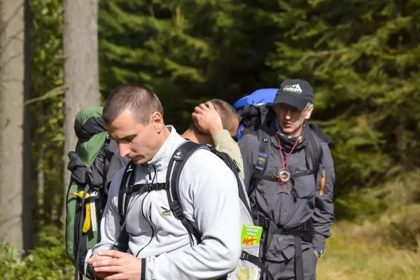Wanderer mit Rucksäcken stehen im Wald und überprüfen Karten oder Geräte
