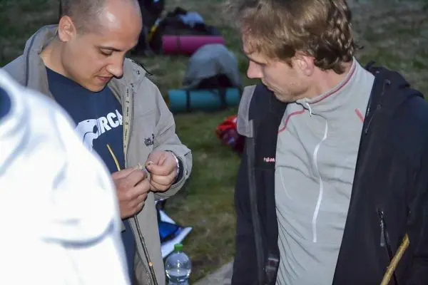 Zwei Personen arbeiten an einem kleinen Gegenstand im Freien
